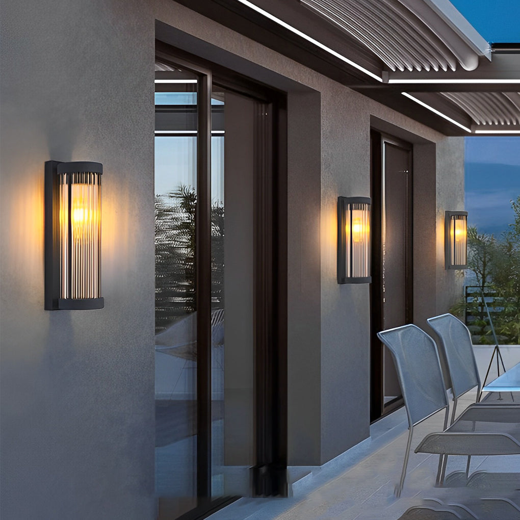 Modern terrace seating area with grey stucco walls displaying multiple elegant outdoor wall mount lights during twilight.