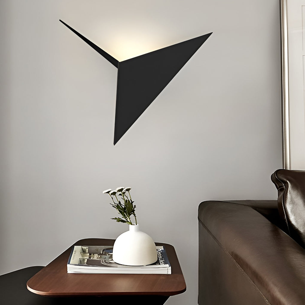 Modern triangle wall sconce illuminating a chic café corner with ambient light.