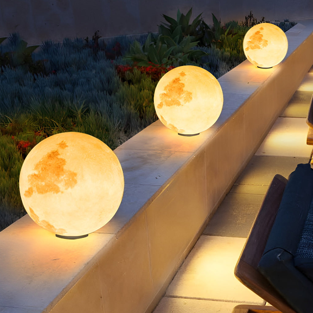 Moon pillar lights with moon surface pattern, illuminating wooden deck near pool.