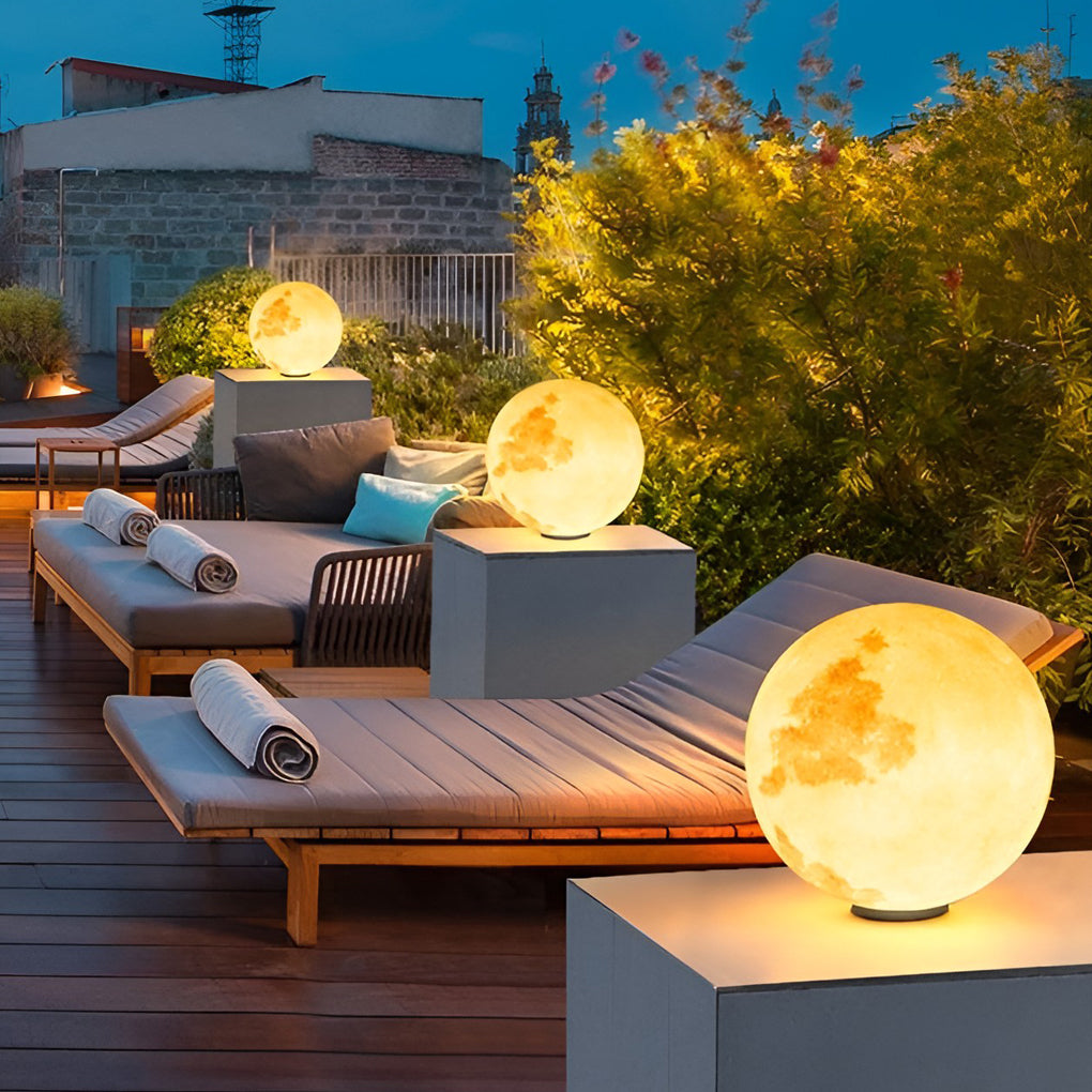 Moon pillar lights with moon texture, enhancing outdoor patio with warm glow.