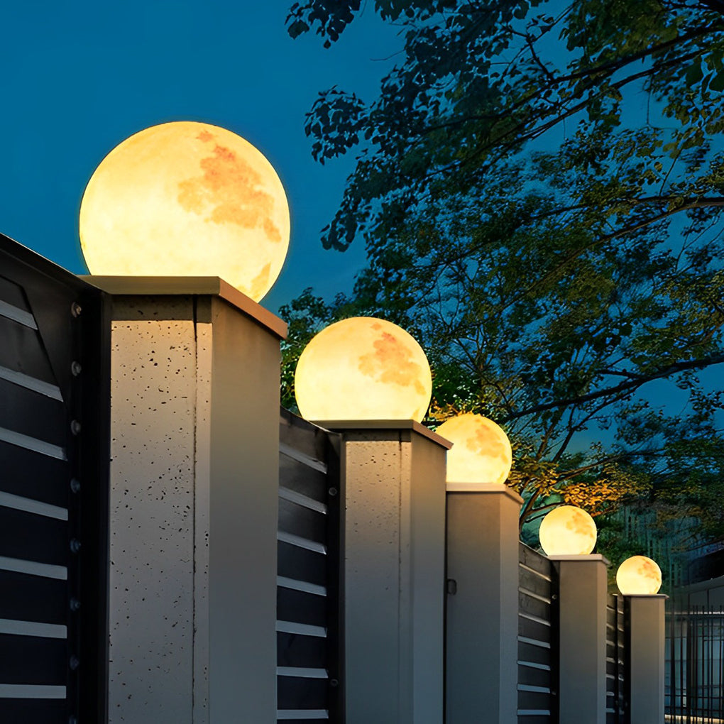 Moon-shaped stone pillar light beside wooden fence and hanging chair in backyard.