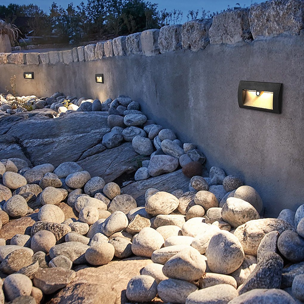 Motion sensor LED step lights enhancing a garden wall with warm glow.