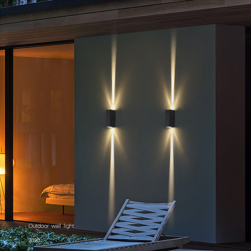 Modern narrow beam wall sconce lighting an exterior corridor, producing dramatic light effects on textured walls.