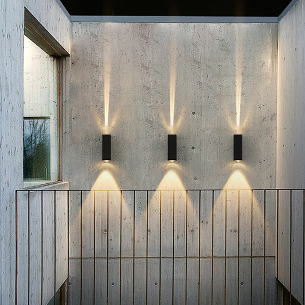 Multiple narrow beam wall sconces aligned on an outdoor wall, creating rhythmic lighting and strong visual symmetry.