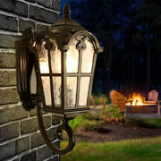 Outdoor black sconce providing warm light on a brick wall near a cozy outdoor seating area.