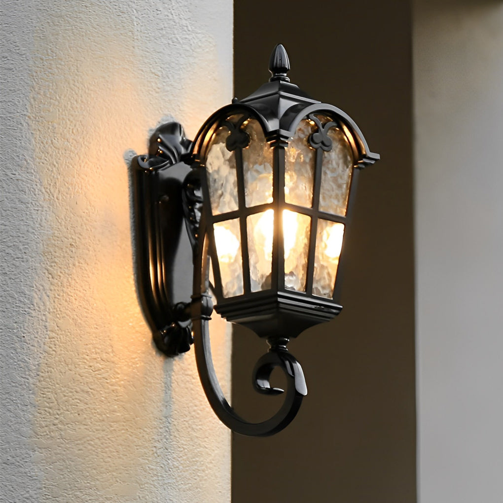 Outdoor black sconce with a decorative design, illuminating a pathway in a garden.