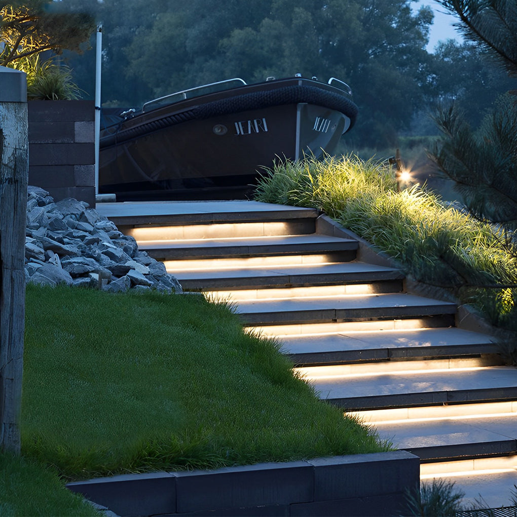Outdoor embedded LED light strips enhancing a garden pathway with continuous illumination.