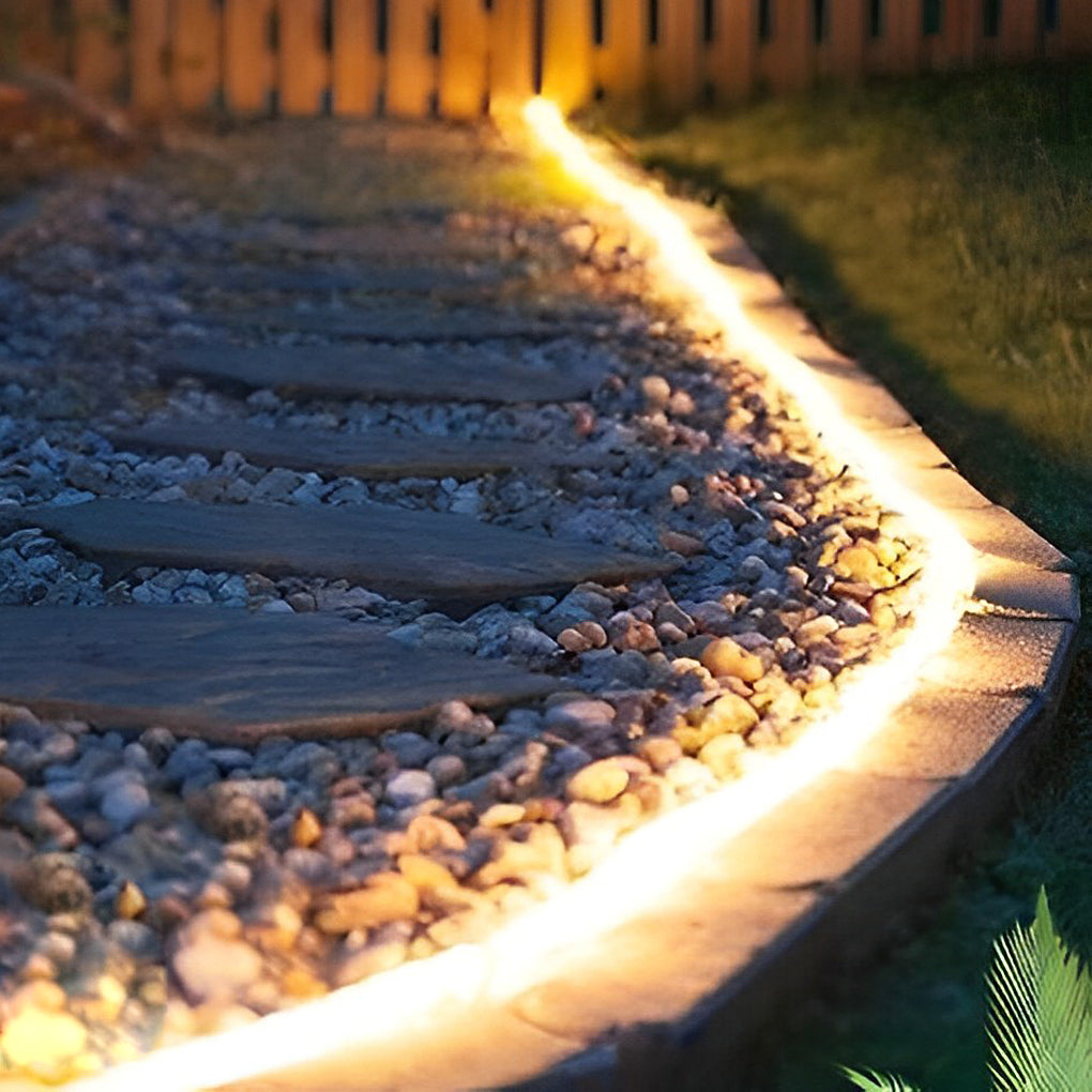 Outdoor embedded LED light strips providing warm light along a stone pathway.
