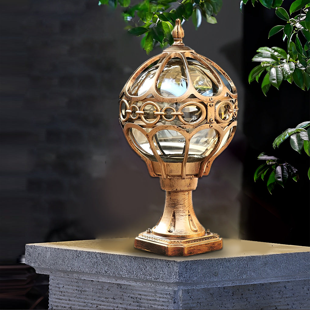Elegant outdoor globe pillar lights with a decorative gold globe, standing on a gray stone base in a garden.