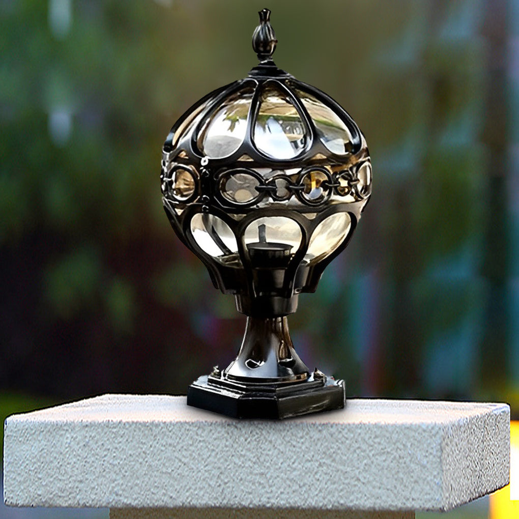 Outdoor globe pillar lights featuring a gold lattice design, illuminating a pathway in a lush green garden.