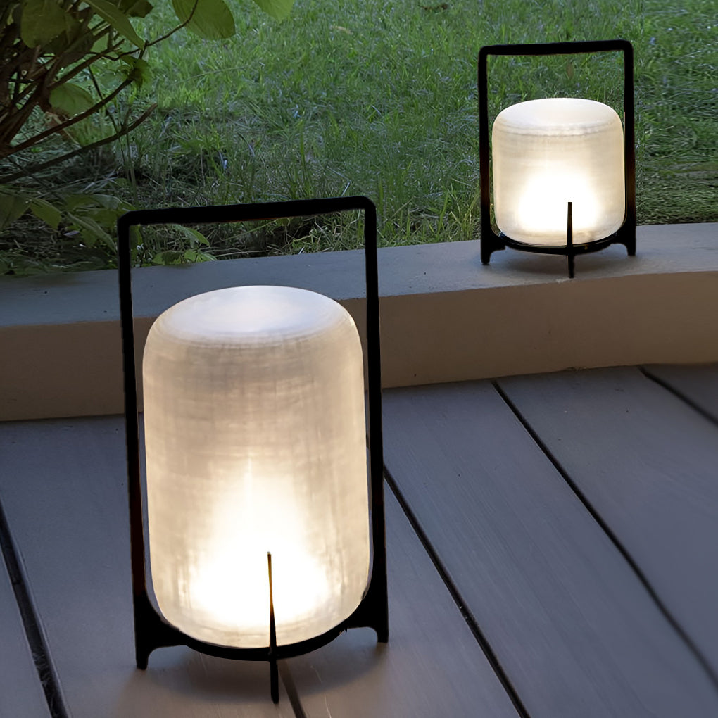 Outdoor modern handle lantern with frosted glass shade on wooden deck beside small table.