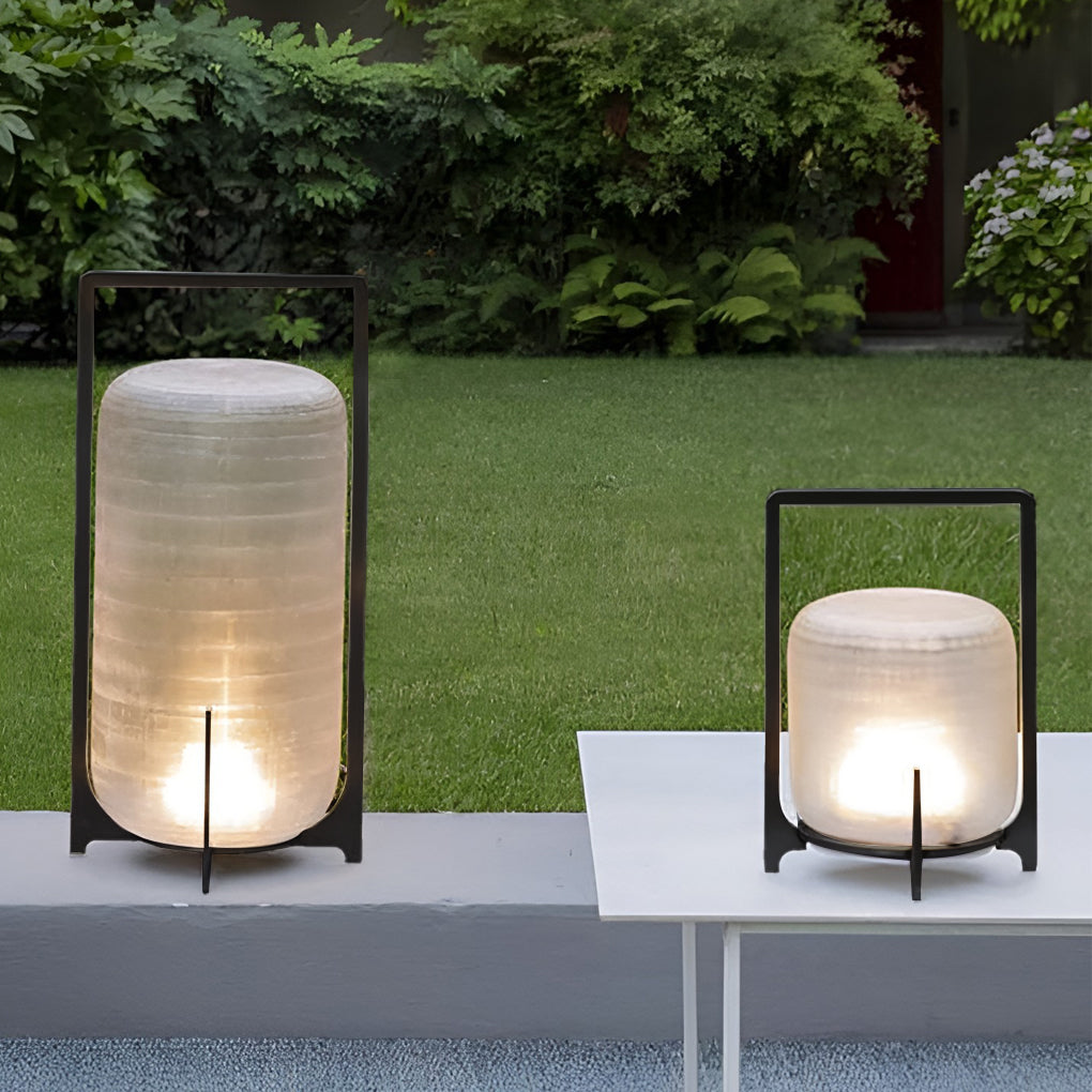 Outdoor modern handle lantern with frosted shade on wooden deck in serene garden setting.