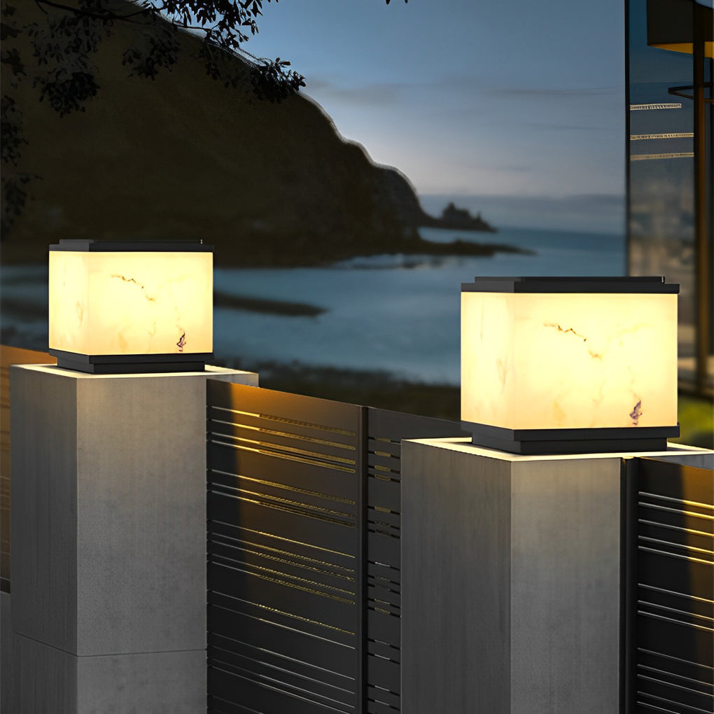 Outdoor stone pillar lights illuminating a pathway by the sea, creating a serene coastal ambiance.