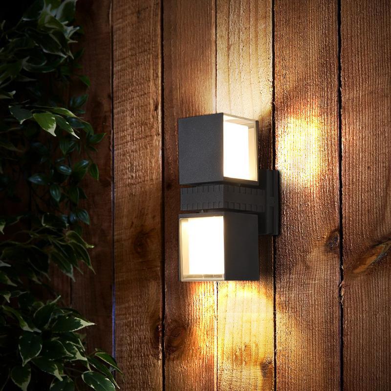 Outside up down wall lights with a minimalist design, mounted on a brick wall.