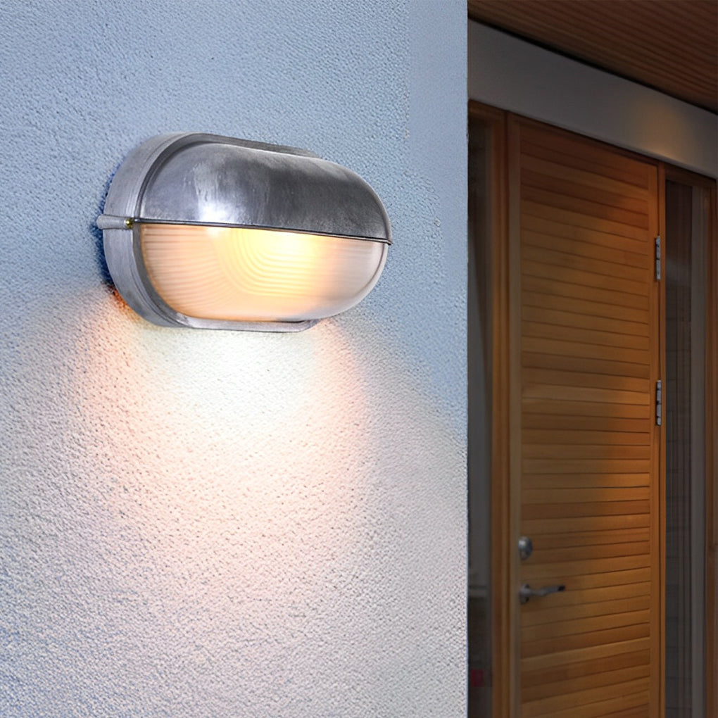Single oval bulkhead outdoor wall light mounted on a light-colored wall near an entryway.