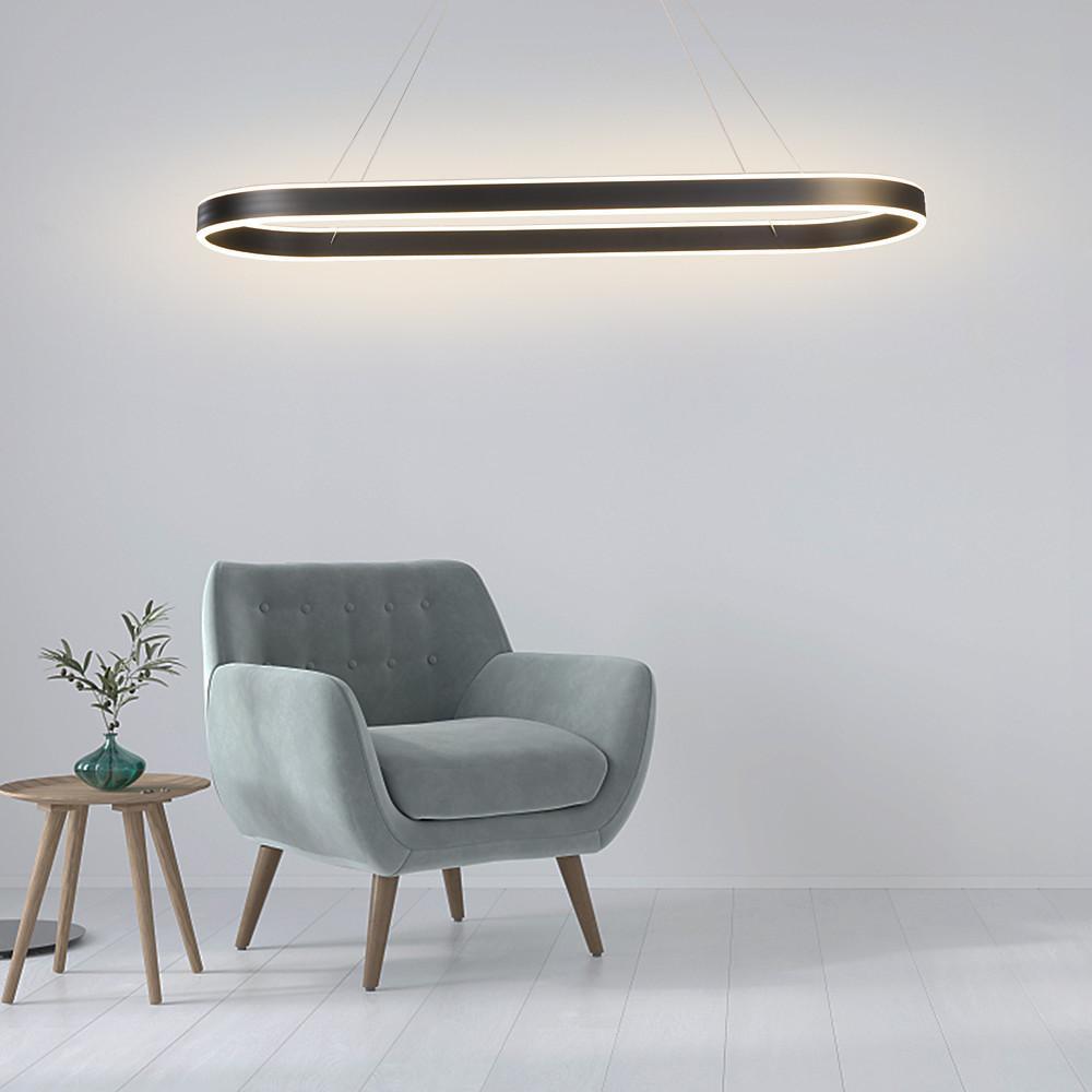 Black oval LED pendant light paired with an accent chair in a modern reading corner.