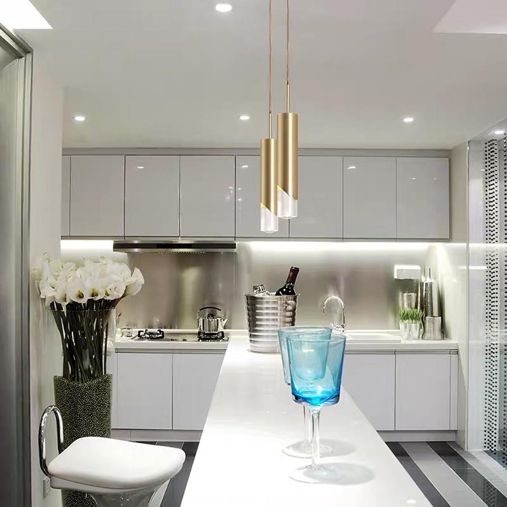 Pair of chic Slanted Gold Cylinder Pendant lights over a luxury white kitchen island desk.