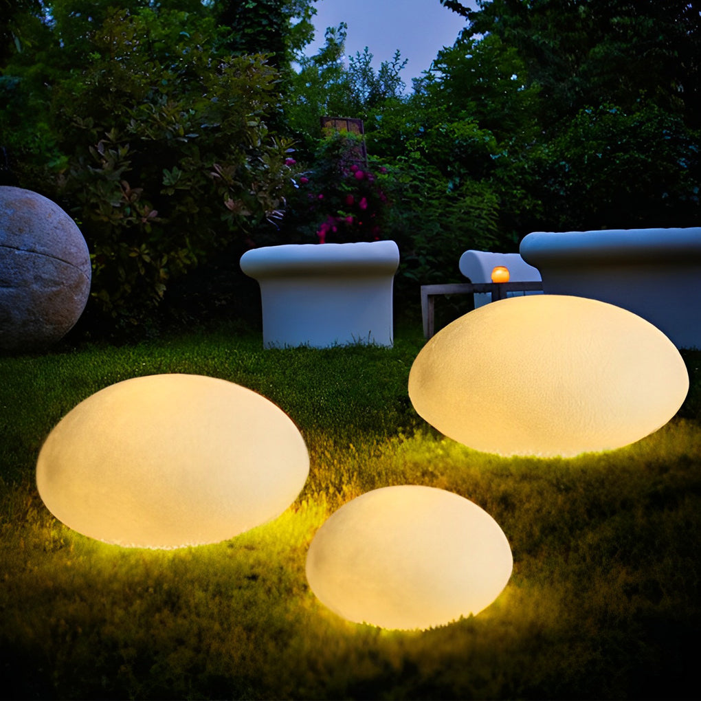 Pebble garden lights illuminating a minimalist outdoor seating area with focused glow.