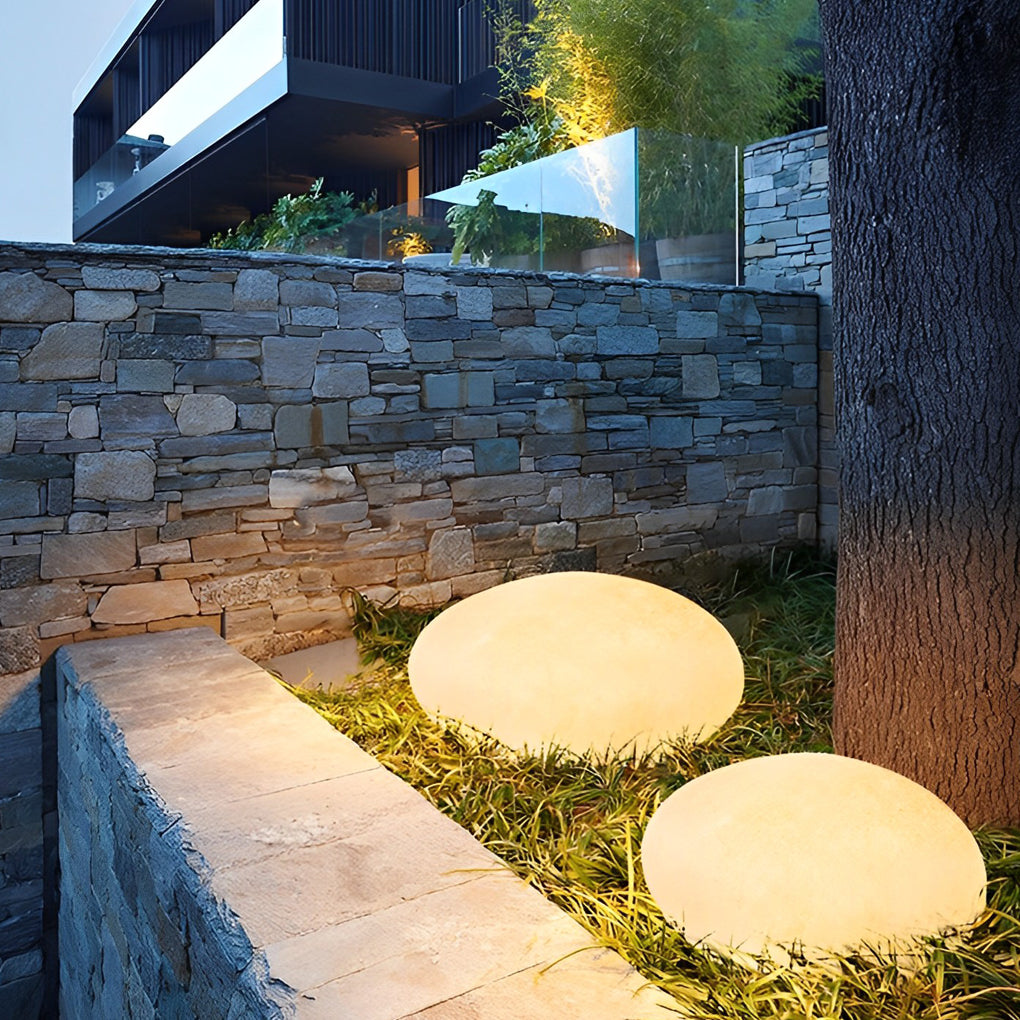 Pebble garden lights providing elegant illumination along a stylish stone wall.
