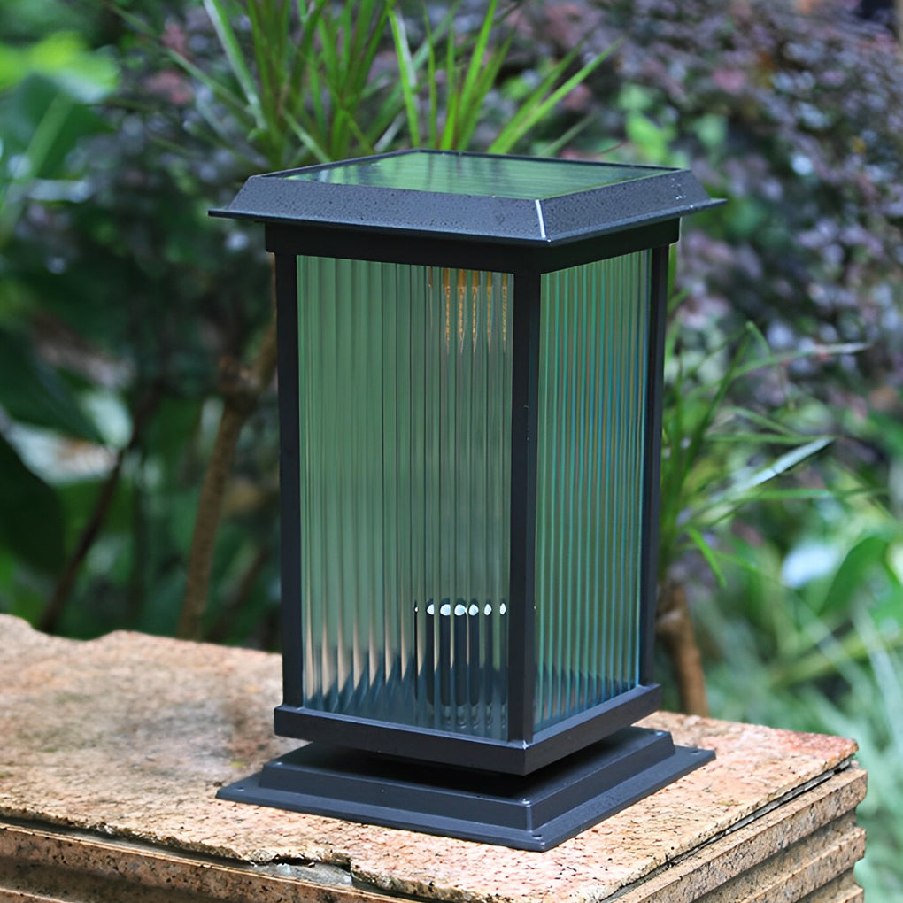 Pillar solar light displayed outdoors on a stone base, surrounded by greenery to highlight its vertical glass design.