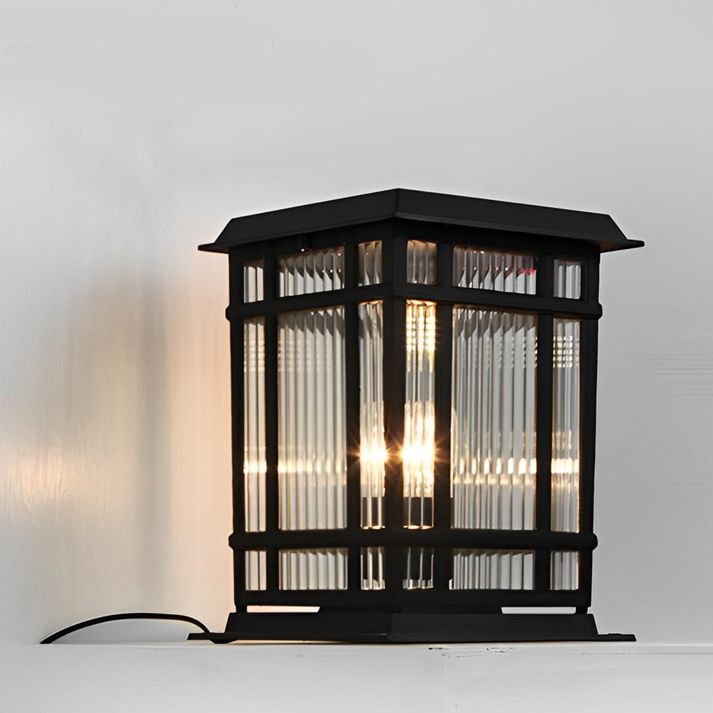 Pillar solar light product image showing black metal frame with textured glass panels in a natural outdoor setting.