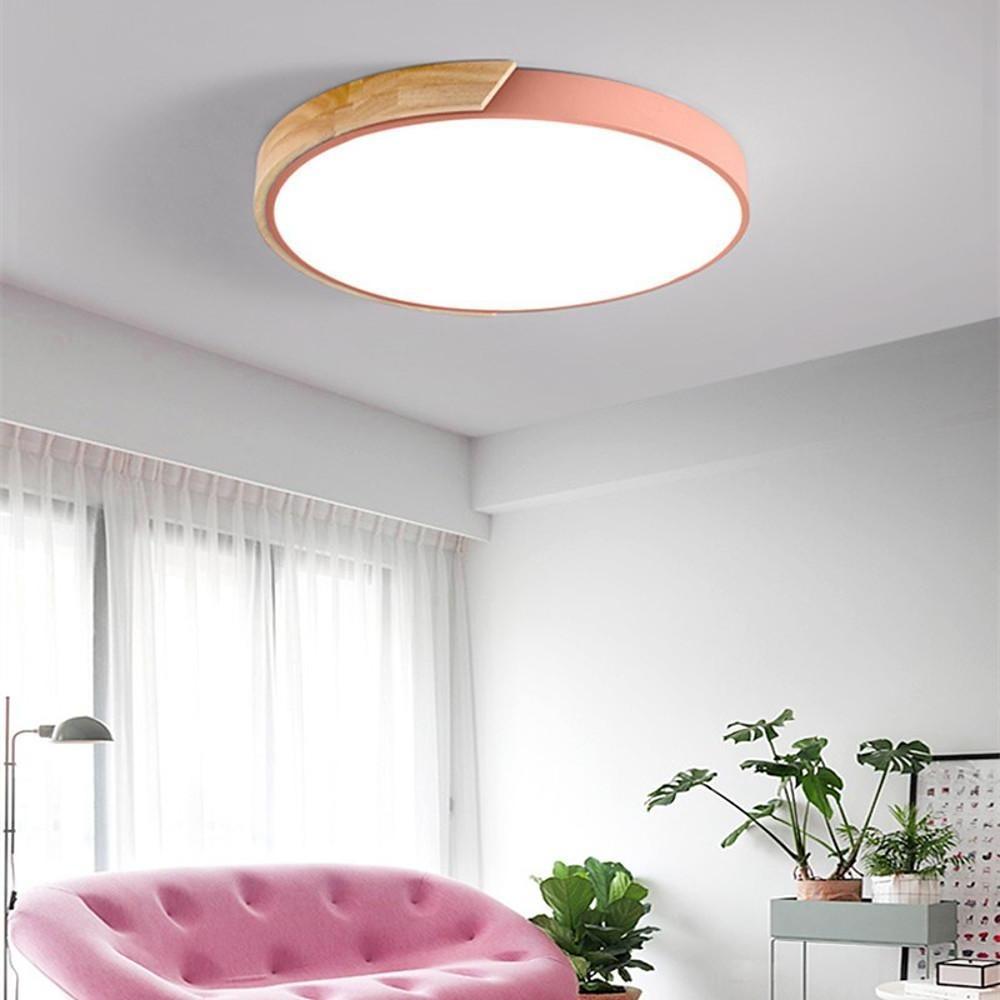 Pink nordic wooden ceiling light glowing brightly in a cozy living room with a pink sofa here.