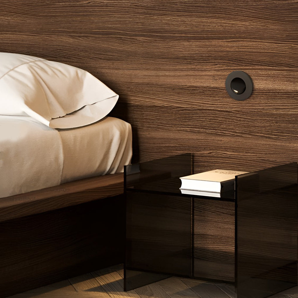 Compact nightstand area illuminated by recessed led reading lamp in modern bedroom.