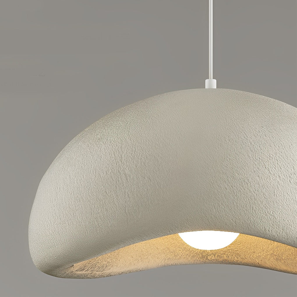 Resin pendant light with a unique, organic texture, hanging above a modern dining setup.