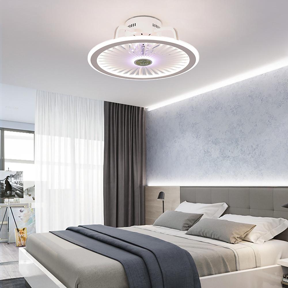 Round ceiling fan with LED light mounted above bed in modern bedroom.
