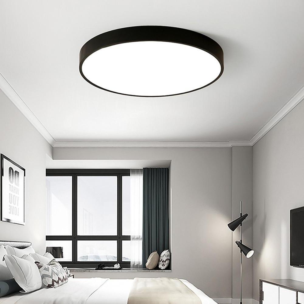 Modern black round led ceiling lights providing soft ambient lighting in a minimalist bedroom.