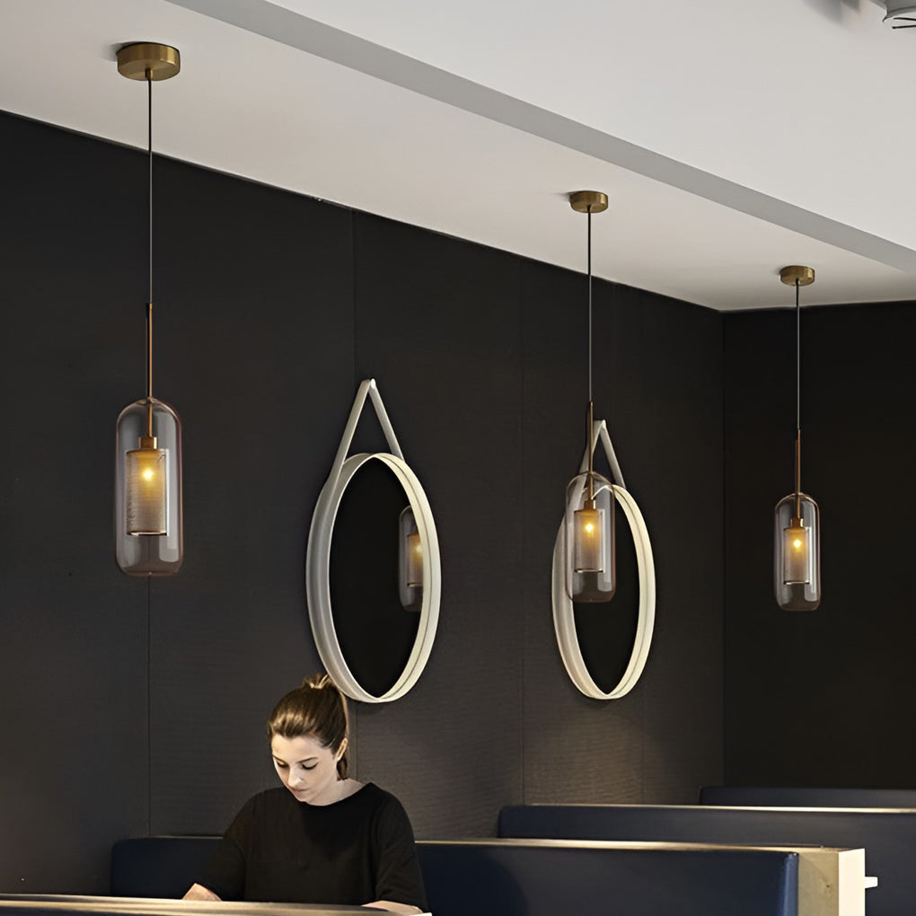 Row of capsule Clear Glass Globe Pendant lights over a desk against a modern dark wall.