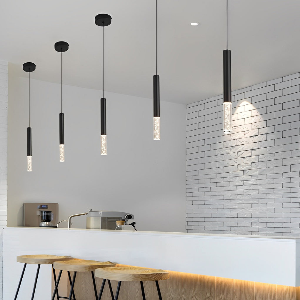 Row of five slim black LED cylinder pendant lights with bubble glass over a kitchen bar top.