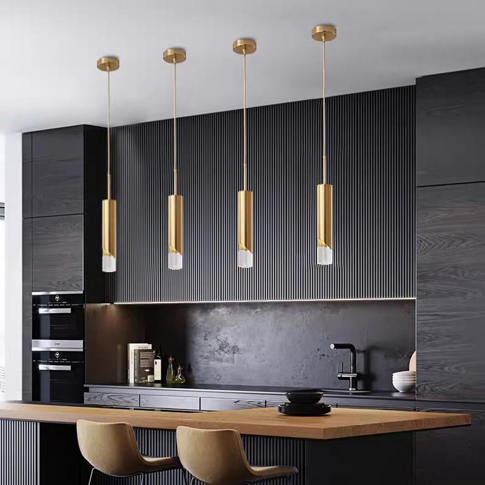 Row of four Slanted Gold Cylinder Pendant lights over a dark luxury kitchen breakfast bar.