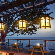 Rustic pendant light hanging over an outdoor dining area with warm, inviting glow.