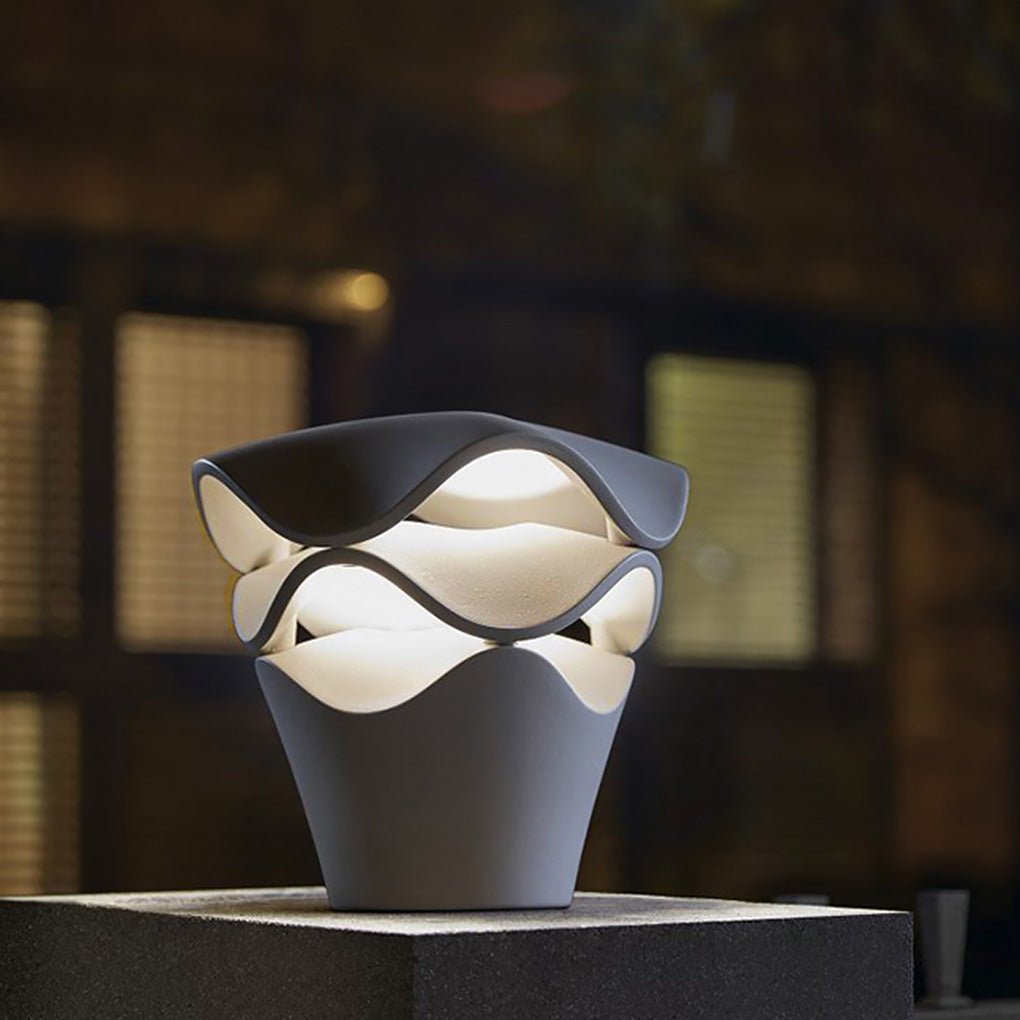 Scenic night shot of a wave design path light on a stone pillar with warm glowing LED diffusion