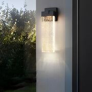 Seeded glass outdoor wall lighting providing elegant illumination near a garden.