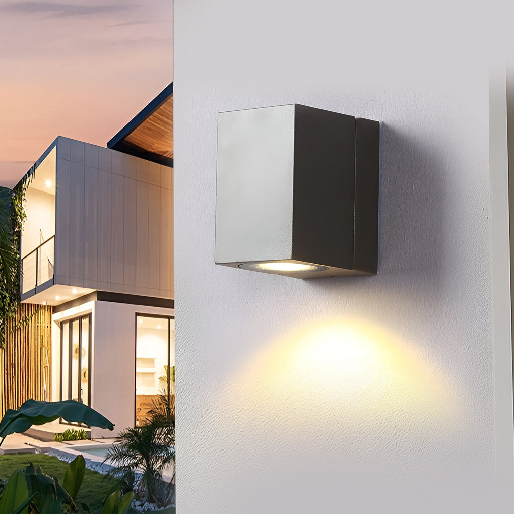 Outdoor sensor wall lights installed on a white wall, casting bright light at dusk.