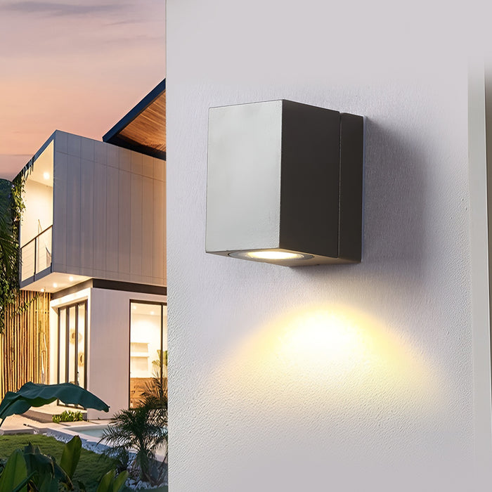 Outdoor sensor wall lights installed on a white wall, casting bright light at dusk.