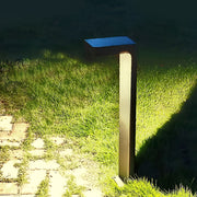 L shaped landscape light with a solar panel, casting soft light on a grassy area.