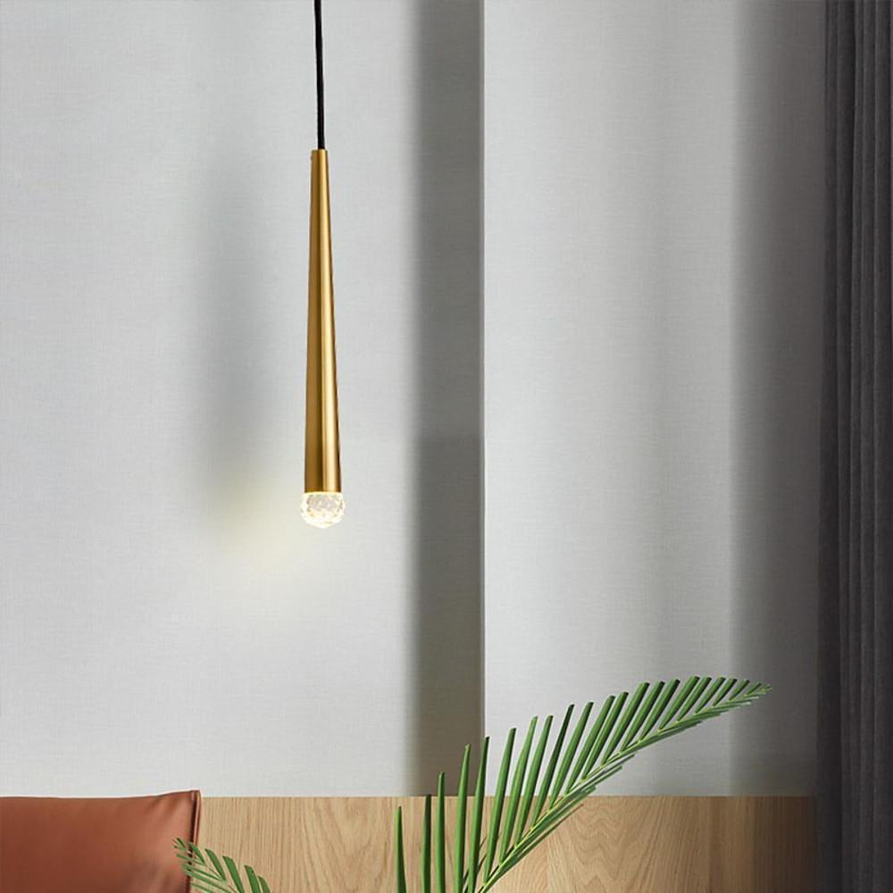 Modern single gold cone pendant light used as a minimalist bedside lamp in a bright room corner.