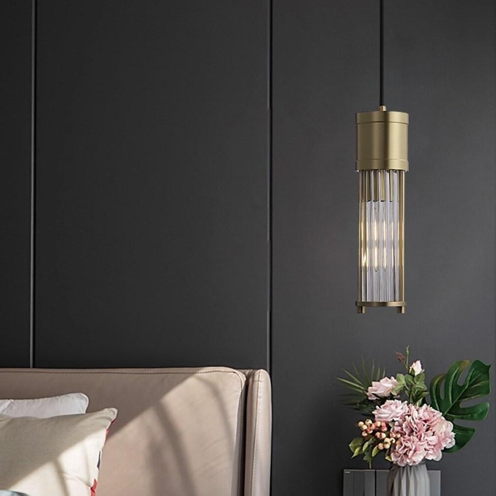 Single gold cylinder pendant light against dark accent wall.