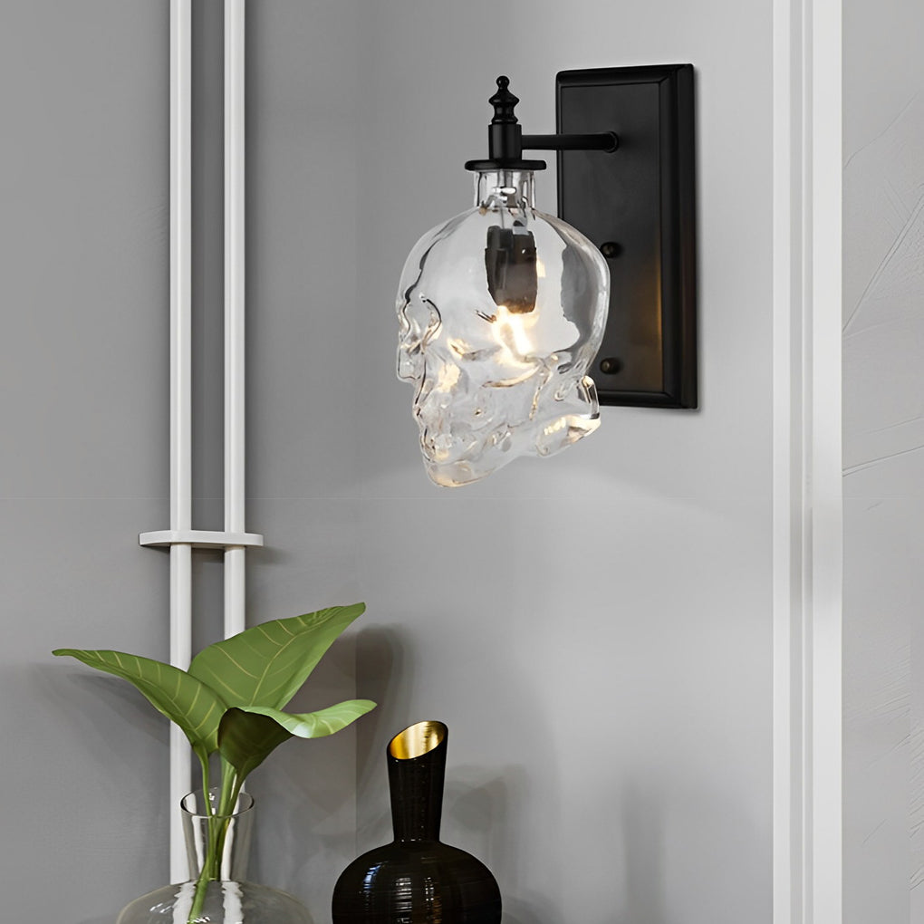 Elegant glass lamp shades for wall lights in skull shape, mounted beside a white wall with minimalist decor and plants.