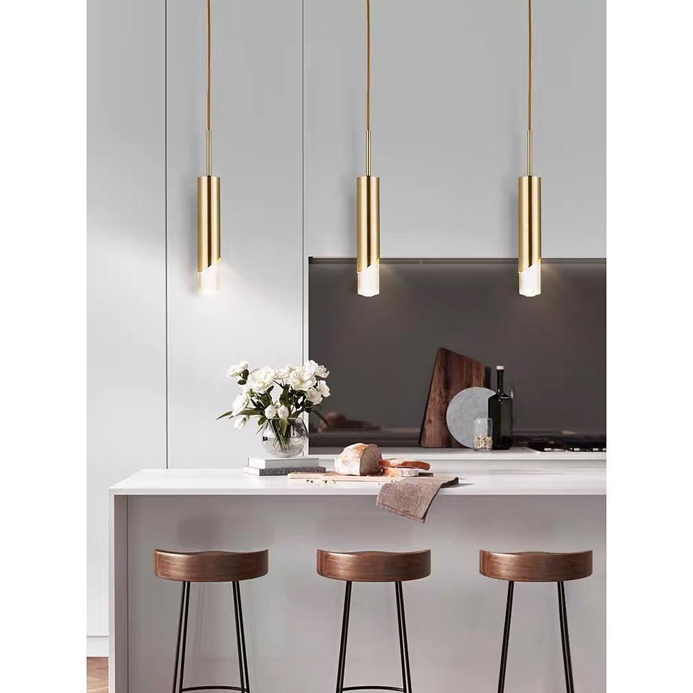 Set of Slanted Gold Cylinder Pendant lights above a kitchen breakfast bar with wooden stools.