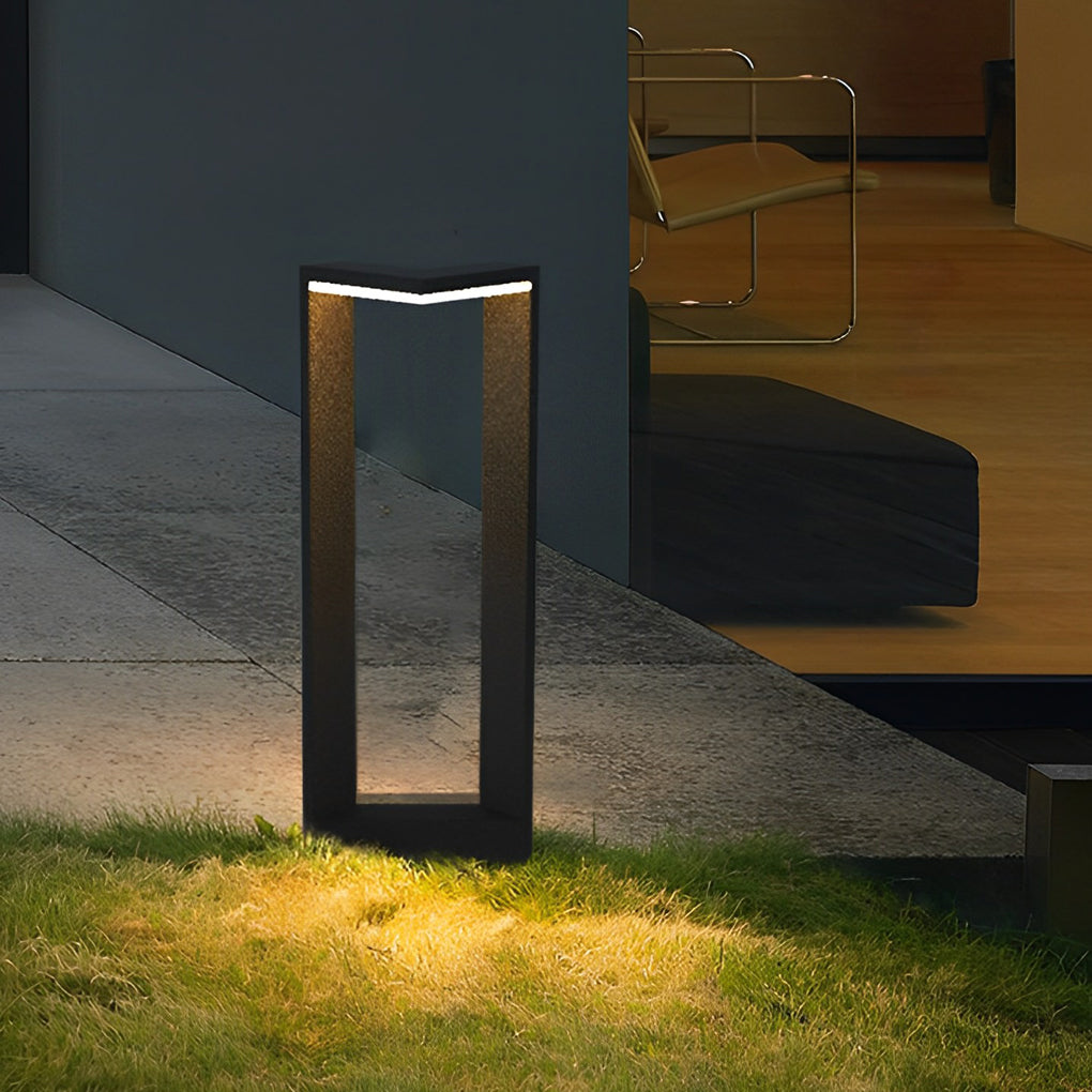 Sleek black architectural garden path light illuminating a lawn near a modern home patio area.