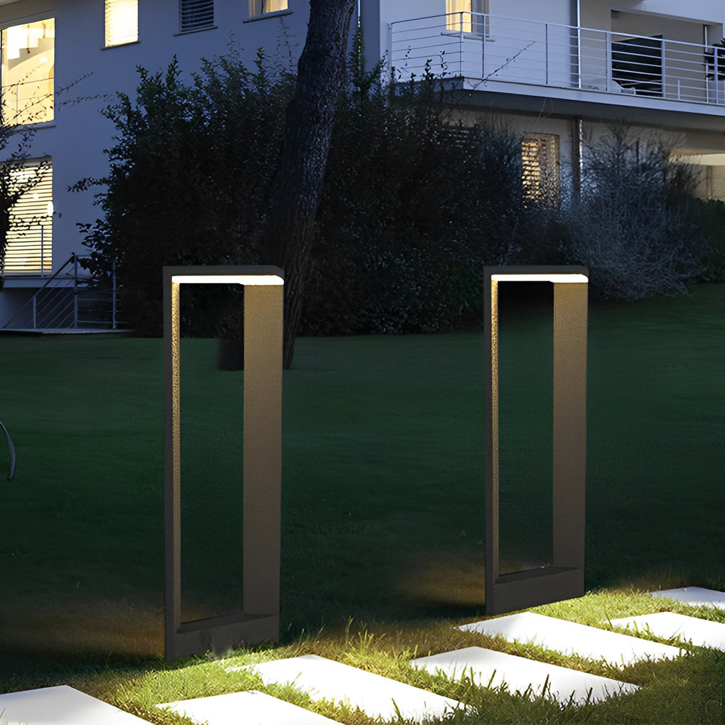 Two sleek architectural garden path lights illuminating white stepping stones on a green lawn.