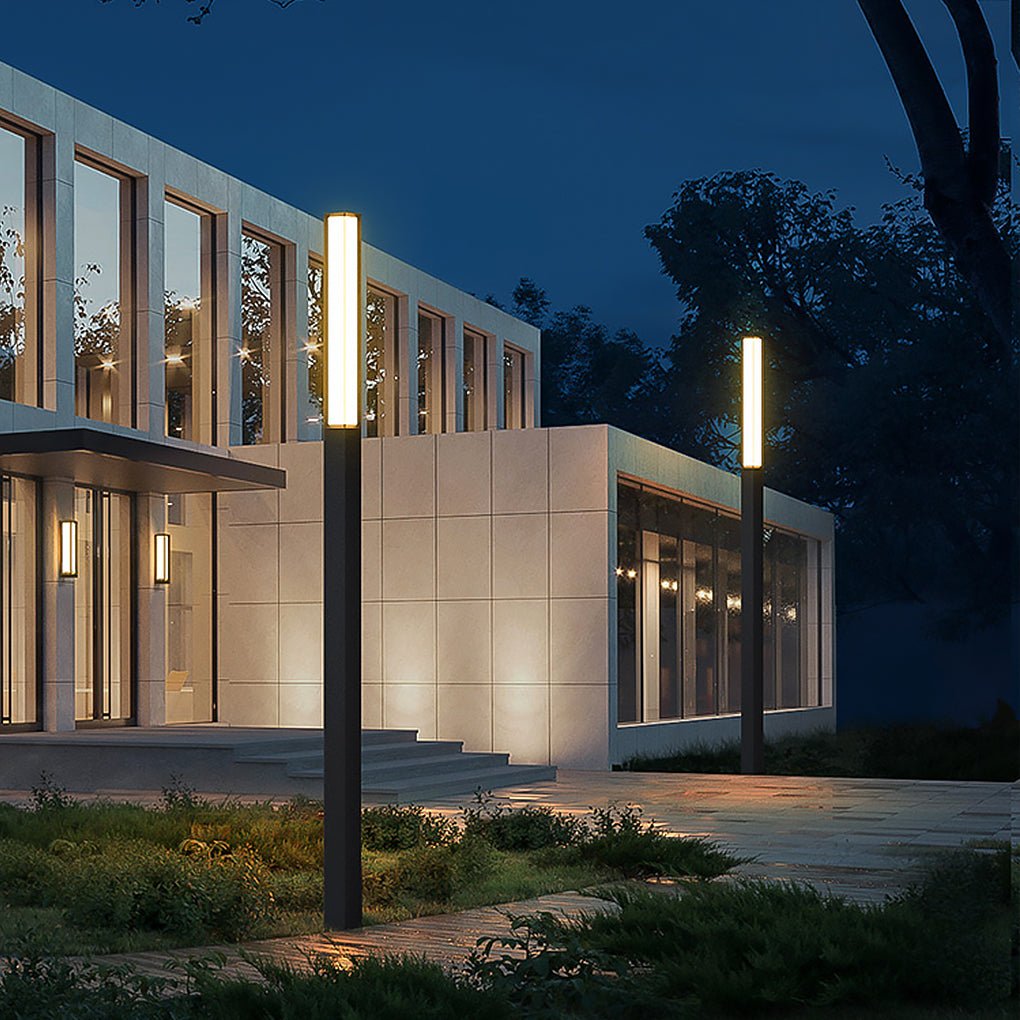 Sleek black outdoor bollard lights lighting up a concrete pathway leading to a modern building.