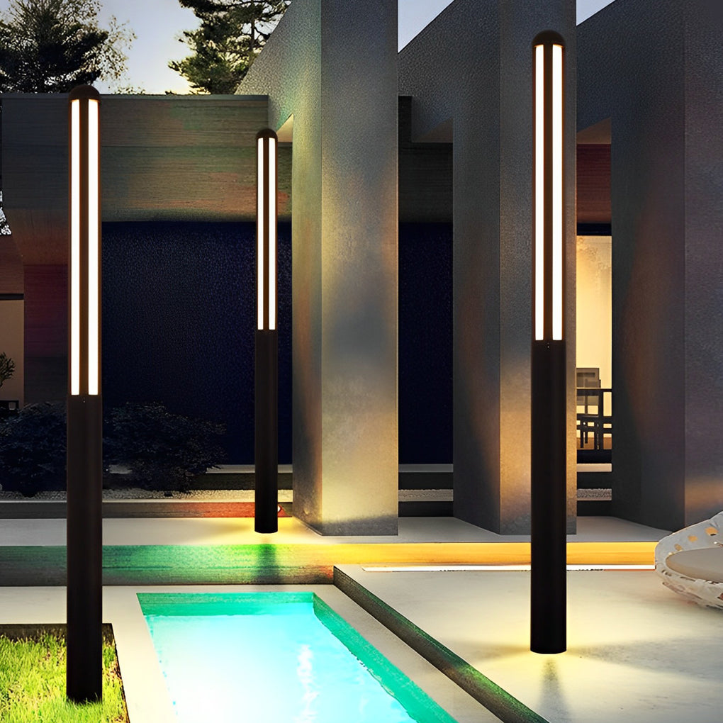 Tall garden bollard light with sleek black design beside modern outdoor sofa.