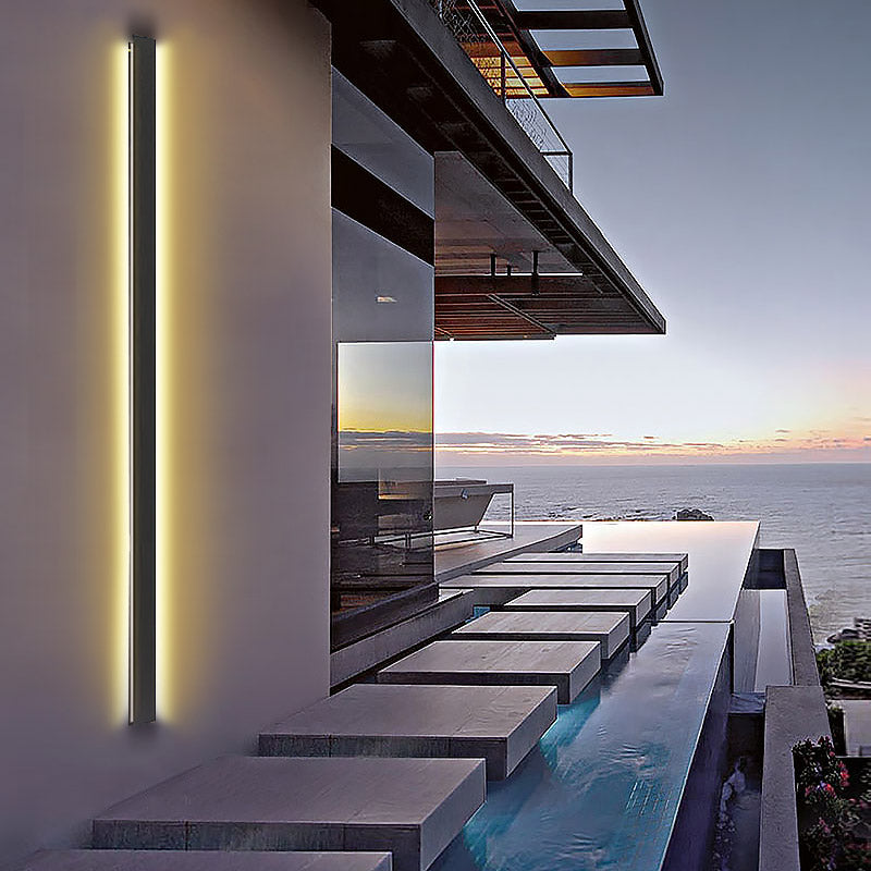 Slim long black outdoor lights installed beside a pool, providing warm and contemporary lighting for outdoor spaces.