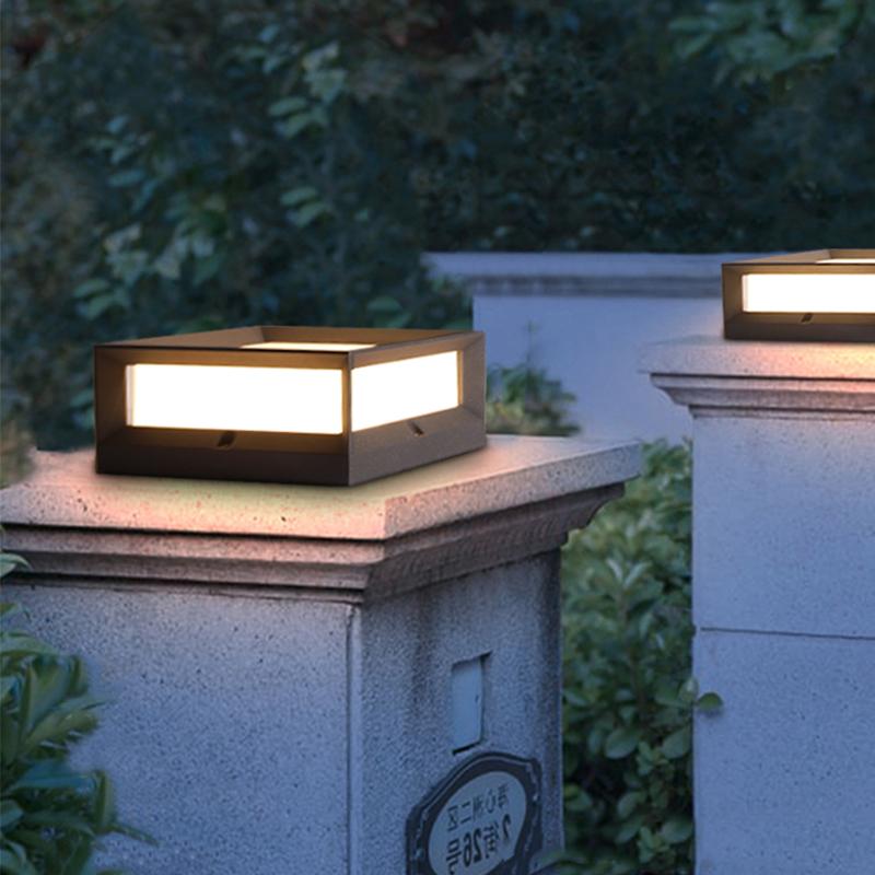 Solar garden pillar lights with black frame and warm glow, mounted on garden wall.