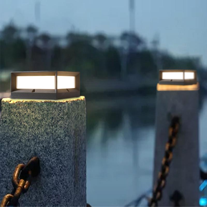 Solar garden pillar lights with black frame, installed near water feature for ambient lighting.